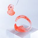 使用限界を超え廃棄されるカプセルトイのカプセルから生まれたオリジナルのアクセサリー「mom(マム)」です。 有限会社三幸の装飾アクリル板製造技術によって作られた、浮遊感のある水中のような表情が美しいアクリル素材を使用。 ミニチュアが入っていたカプセルからインスピレーションを受け、豆型のピースが包み込まれるようにデザインされたイヤーアクセサリーです。 イアーカフとピアス(イアリング)をセパレートで使用できます。KiNaKoとのコラボレーションによって生まれました。 デザイン/KiNaKo