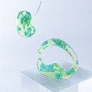 使用限界を超え廃棄されるカプセルトイのカプセルから生まれたオリジナルのアクセサリー「mom（マム）」です。 有限会社三幸の装飾アクリル板製造技術によって作られた、浮遊感のある水中のような表情が美しいアクリル素材を使用。 ミニチュアが入っていたカプセルからインスピレーションを受け、豆型のピースが包み込まれるようにデザインされたイヤーアクセサリーです。 イアーカフとピアス（イアリング）をセパレートで使用できます。KiNaKoとのコラボレーションによって生まれました。 デザイン/KiNaKo 