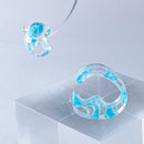 使用限界を超え廃棄されるカプセルトイのカプセルから生まれたオリジナルのアクセサリー「mom（マム）」です。 有限会社三幸の装飾アクリル板製造技術によって作られた、浮遊感のある水中のような表情が美しいアクリル素材を使用。 ミニチュアが入っていたカプセルからインスピレーションを受け、豆型のピースが包み込まれるようにデザインされたイヤーアクセサリーです。 イアーカフとピアス（イアリング）をセパレートで使用できます。KiNaKoとのコラボレーションによって生まれました。 デザイン/KiNaKo 