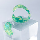 使用限界を超え廃棄されるカプセルトイのカプセルから生まれたオリジナルのアクセサリー「mom（マム）」です。 有限会社三幸の装飾アクリル板製造技術によって作られた、浮遊感のある水中のような表情が美しいアクリル素材を使用。 ミニチュアが入っていたカプセルからインスピレーションを受け、豆型のピースが包み込まれるようにデザインされたイヤーアクセサリーです。 イアーカフとピアス（イアリング）をセパレートで使用できます。KiNaKoとのコラボレーションによって生まれました。 デザイン/KiNaKo 