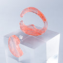 使用限界を超え廃棄されるカプセルトイのカプセルから生まれたオリジナルのアクセサリー「mom（マム）」です。 有限会社三幸の装飾アクリル板製造技術によって作られた、浮遊感のある水中のような表情が美しいアクリル素材を使用。 ミニチュアが入っていたカプセルからインスピレーションを受け、豆型のピースが包み込まれるようにデザインされたイヤーアクセサリーです。 イアーカフとピアス（イアリング）をセパレートで使用できます。KiNaKoとのコラボレーションによって生まれました。 デザイン/KiNaKo 