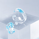 使用限界を超え廃棄されるカプセルトイのカプセルから生まれたオリジナルのアクセサリー「mom（マム）」です。 有限会社三幸の装飾アクリル板製造技術によって作られた、浮遊感のある水中のような表情が美しいアクリル素材を使用。 ミニチュアが入っていたカプセルからインスピレーションを受け、豆型のピースが包み込まれるようにデザインされたイヤーアクセサリーです。 イアーカフとピアス（イアリング）をセパレートで使用できます。KiNaKoとのコラボレーションによって生まれました。 デザイン/KiNaKo 