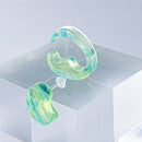 使用限界を超え廃棄されるカプセルトイのカプセルから生まれたオリジナルのアクセサリー「mom（マム）」です。 有限会社三幸の装飾アクリル板製造技術によって作られた、浮遊感のある水中のような表情が美しいアクリル素材を使用。 ミニチュアが入っていたカプセルからインスピレーションを受け、豆型のピースが包み込まれるようにデザインされたイヤーアクセサリーです。 イアーカフとピアス（イアリング）をセパレートで使用できます。KiNaKoとのコラボレーションによって生まれました。 デザイン/KiNaKo 